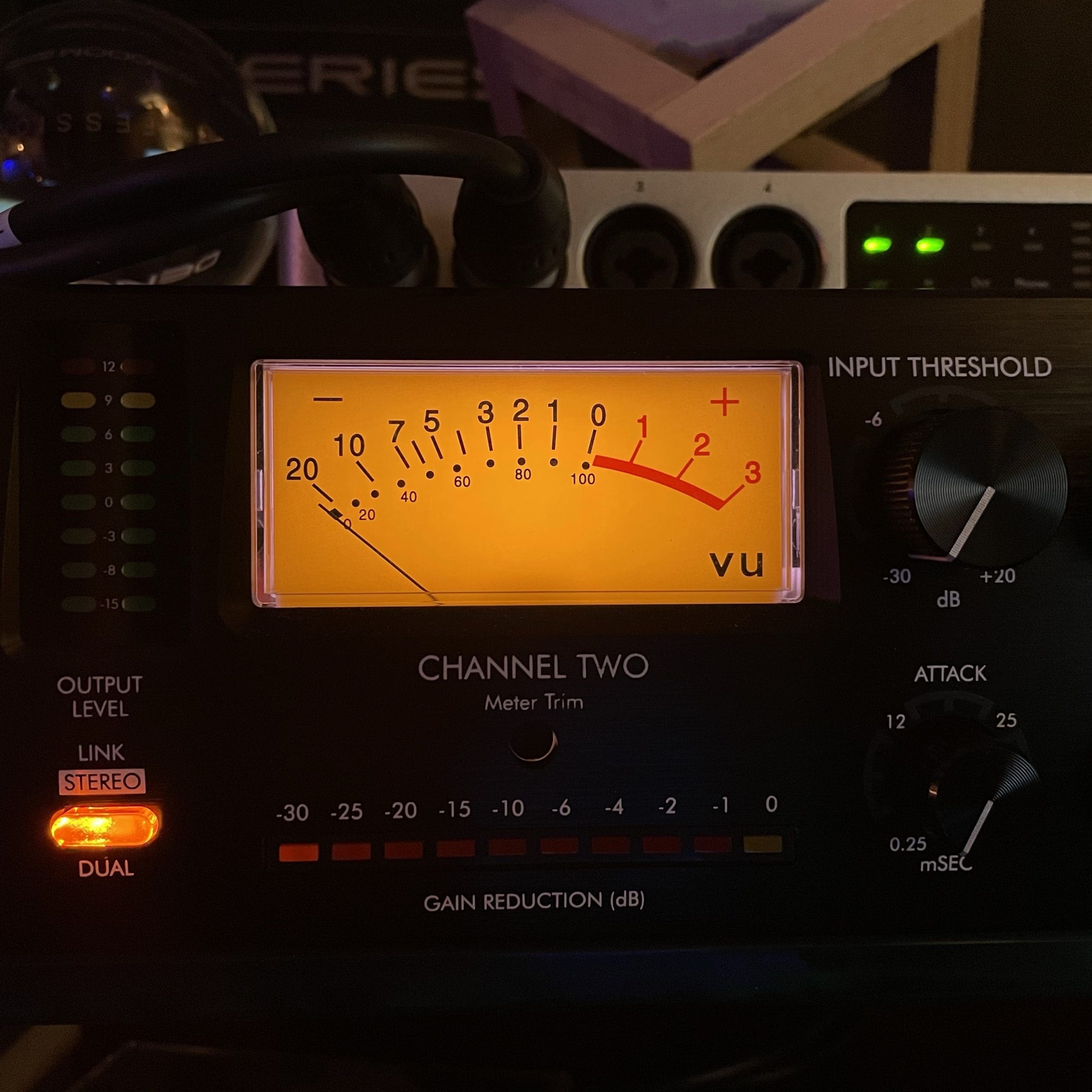 Close-up of a vintage analog VU meter with a glowing scale and physical needle